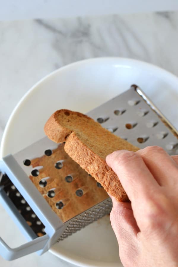 grating toasted bread to make bread crumbs