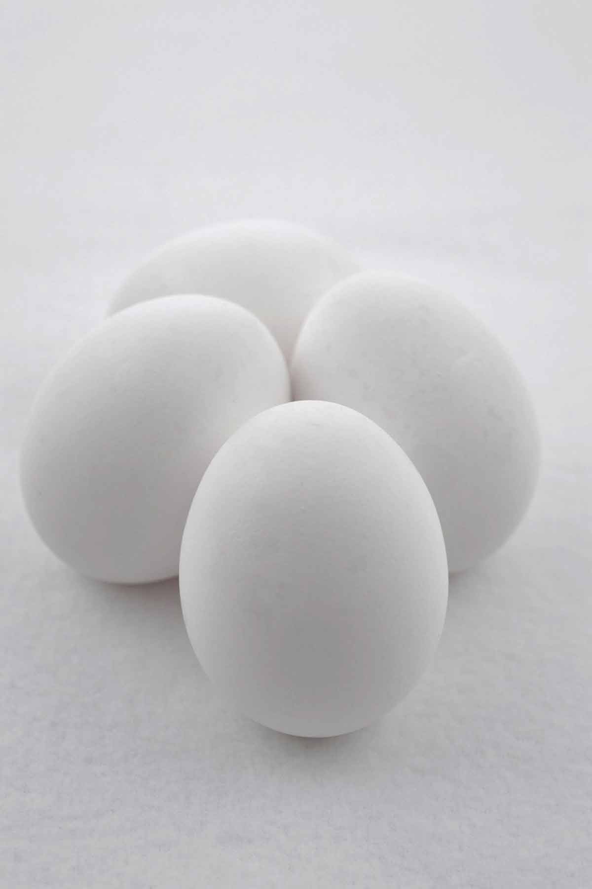 Four white eggs on the counter.