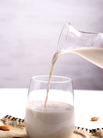 pouring homemade almond milk into glass