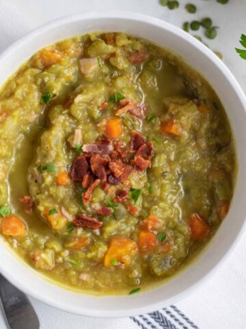 Bowl of split pea soup garnished with bacon.