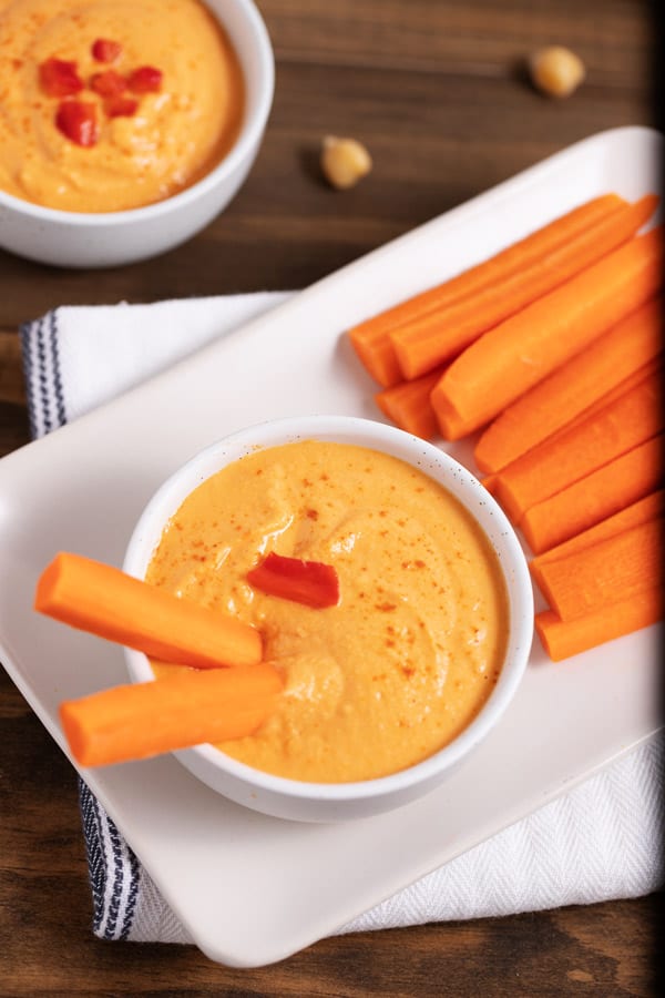 bowl of red pepper hummus and carrot sticks