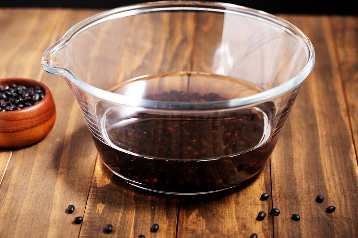 A bowl of water soaking dry black beans.