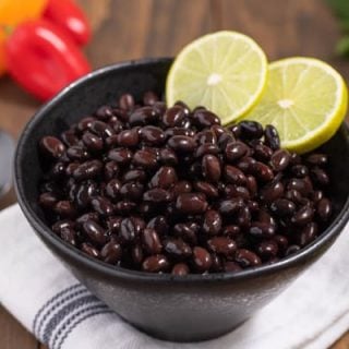 closeup of cooked black beans with lime slices