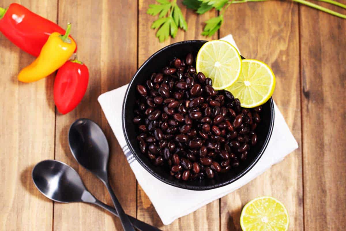 Bowl of homemade black beans garnished with lime wedges.
