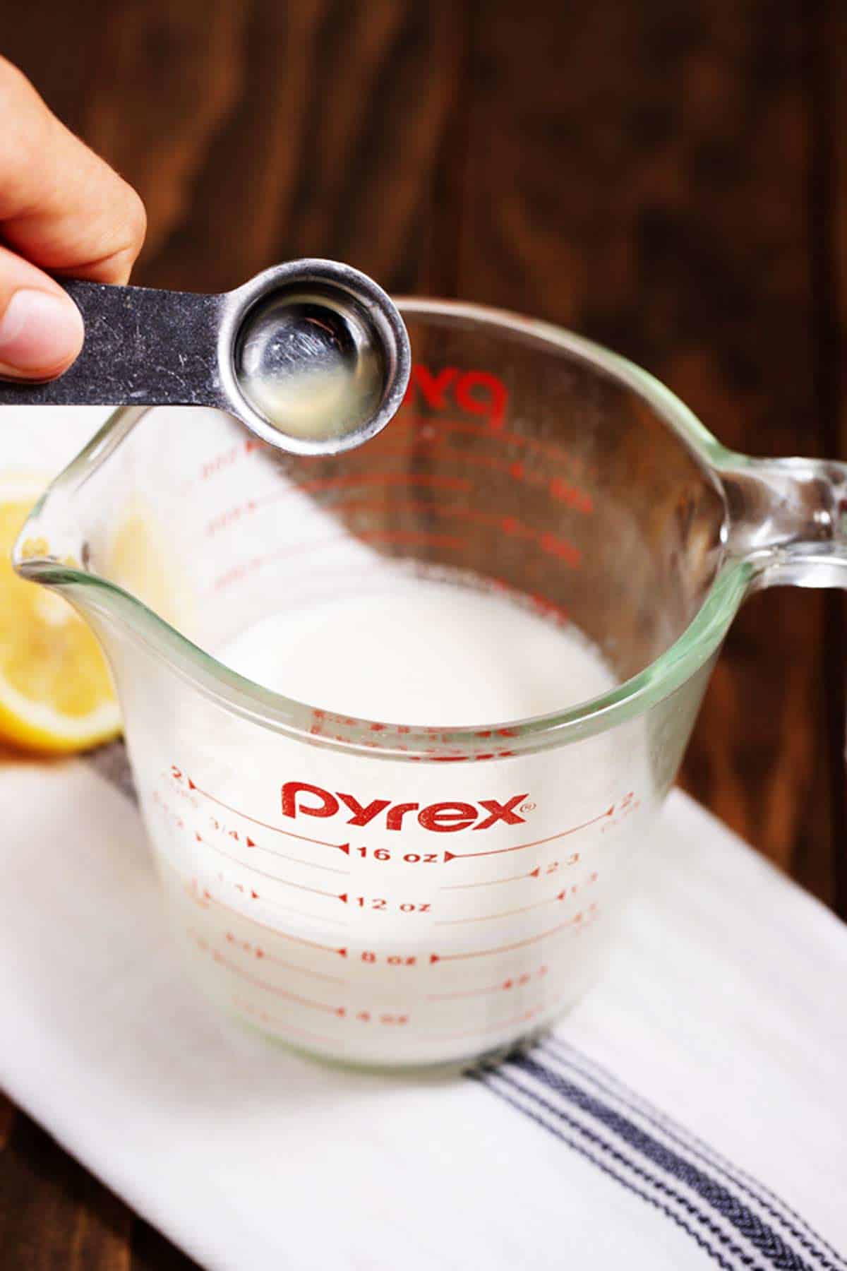 Pouring lemon juice into milk to make a buttermilk substitute.