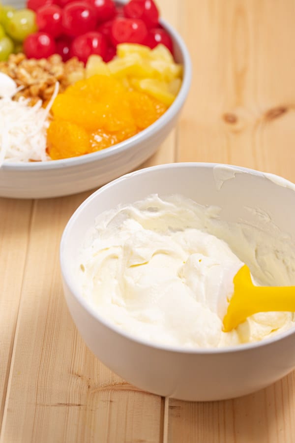 whipped cream and sour cream with bowl of fruit in background