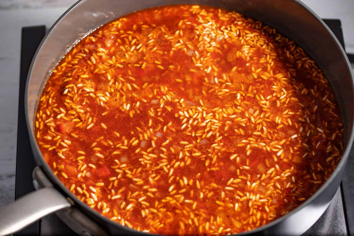 toasted rice covered in liquid, ready to be cooked