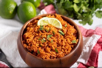 bowl of seasoned rice on napkin with lime wedges and snips of cilantro