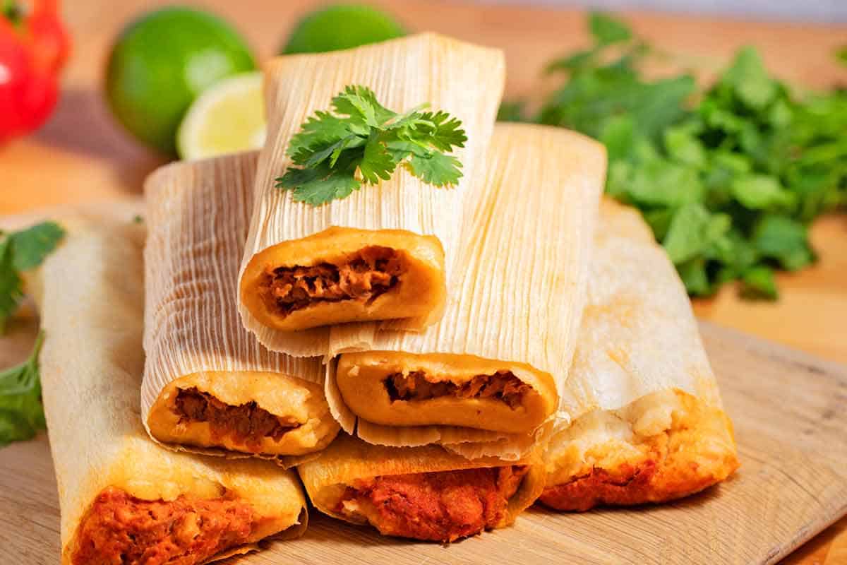 Stack of tamales on a cutting board.