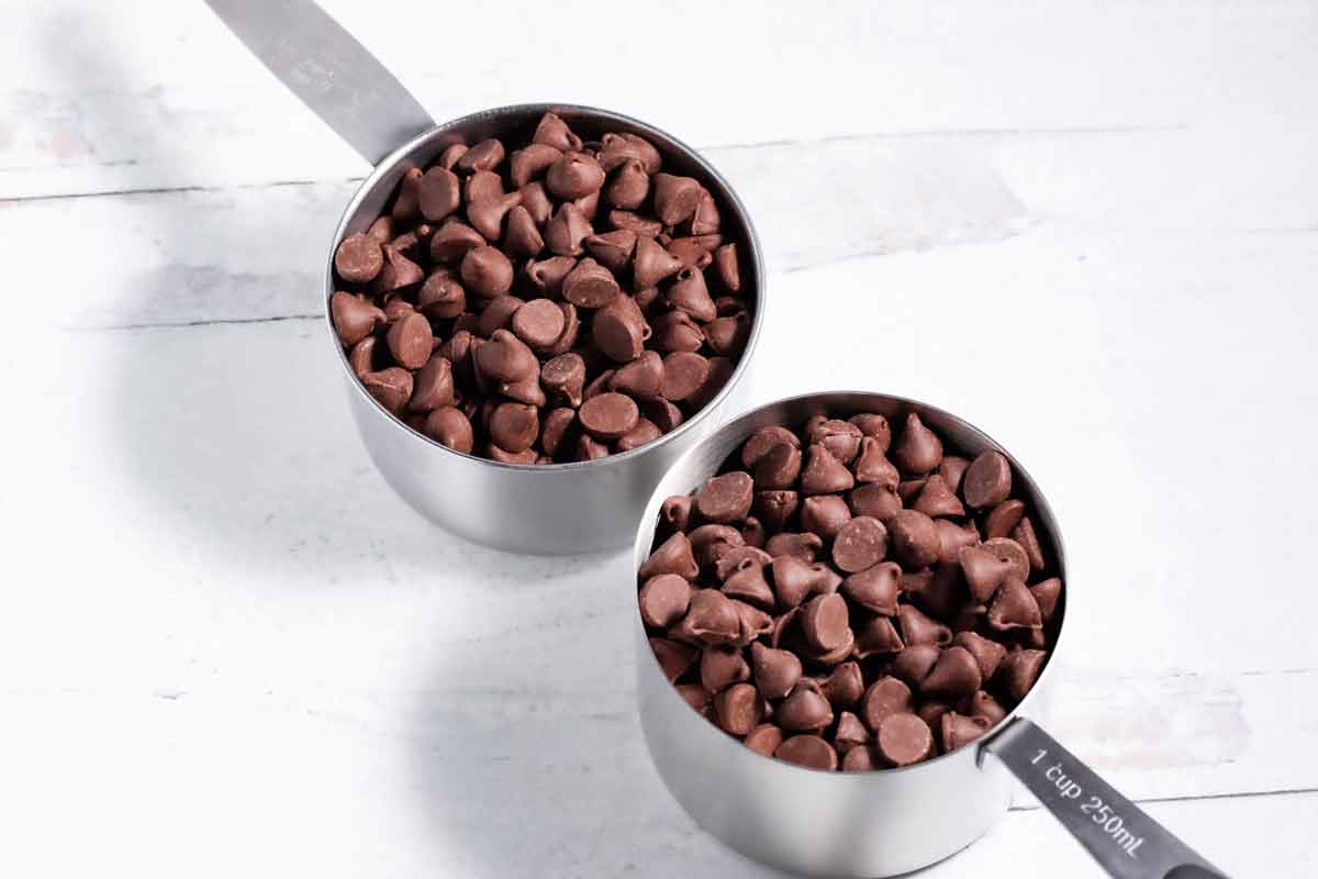 Two cups of chocolate chips on the counter.