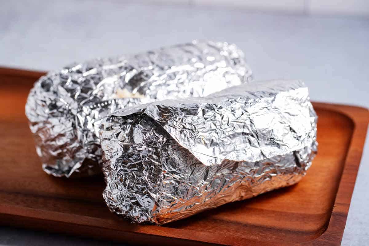 Two burritos wrapped in foil.