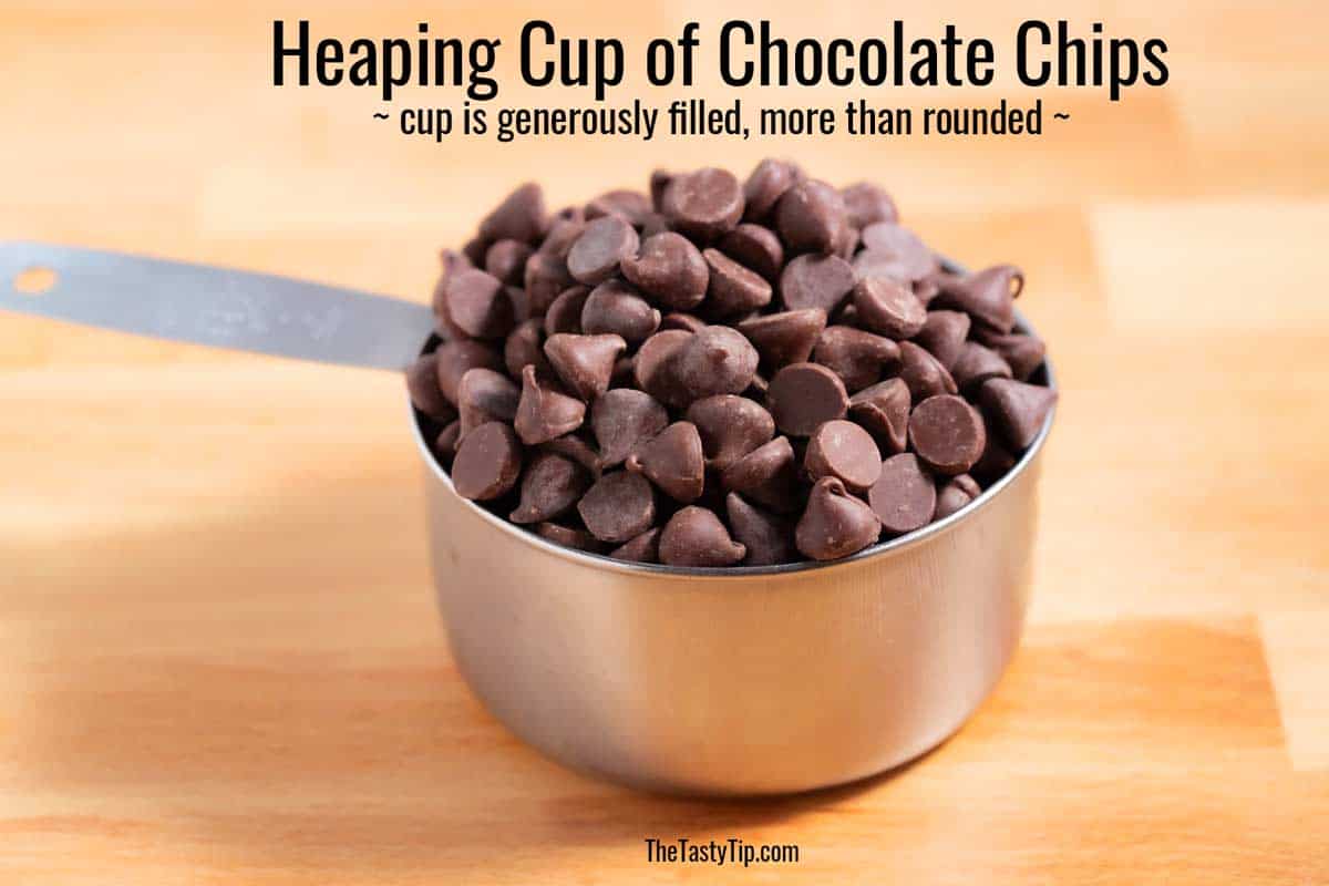 Heaping cup of chocolate chips on the counter.