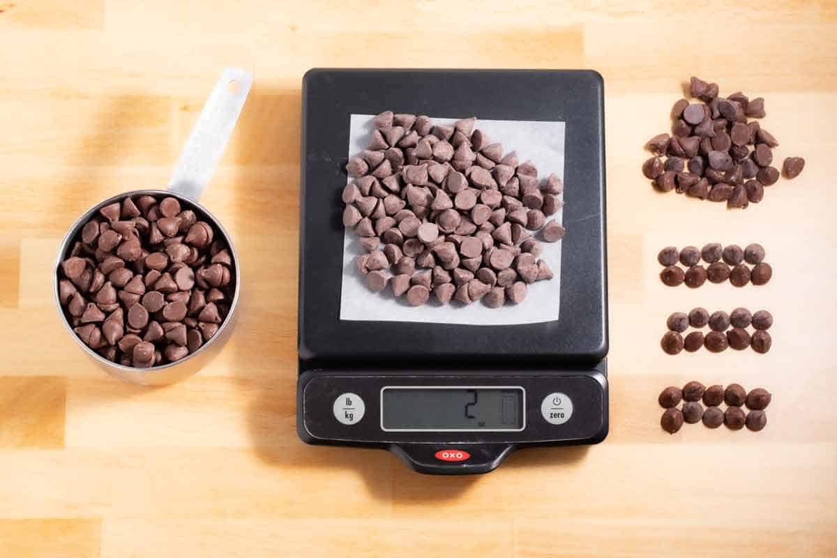 Chocolate chips in a cup, on a kitchen scale, and laid out on the counter.