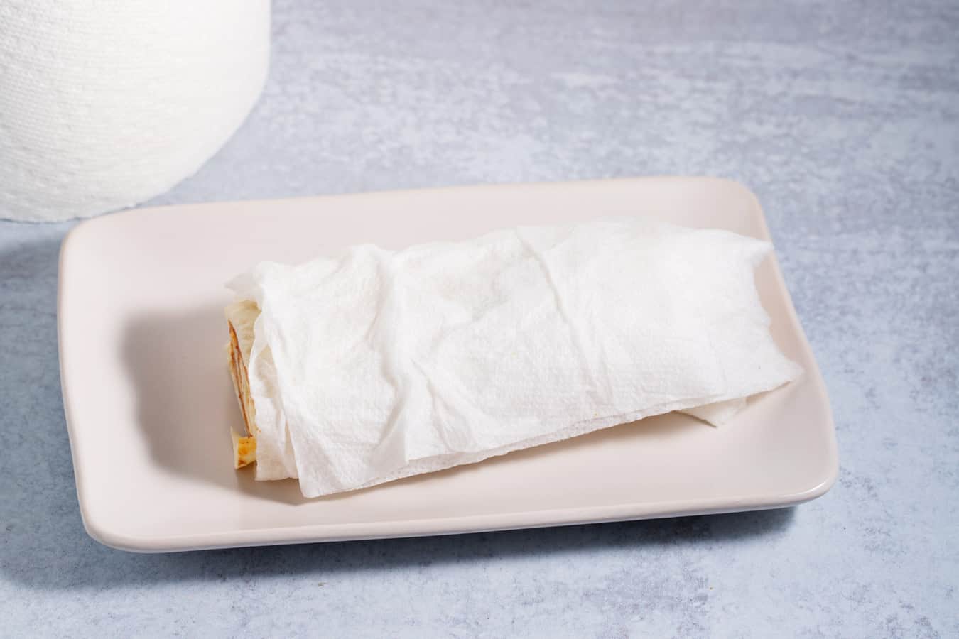 cold burrito wrapped in damp paper towel ready to reheat in the microwave