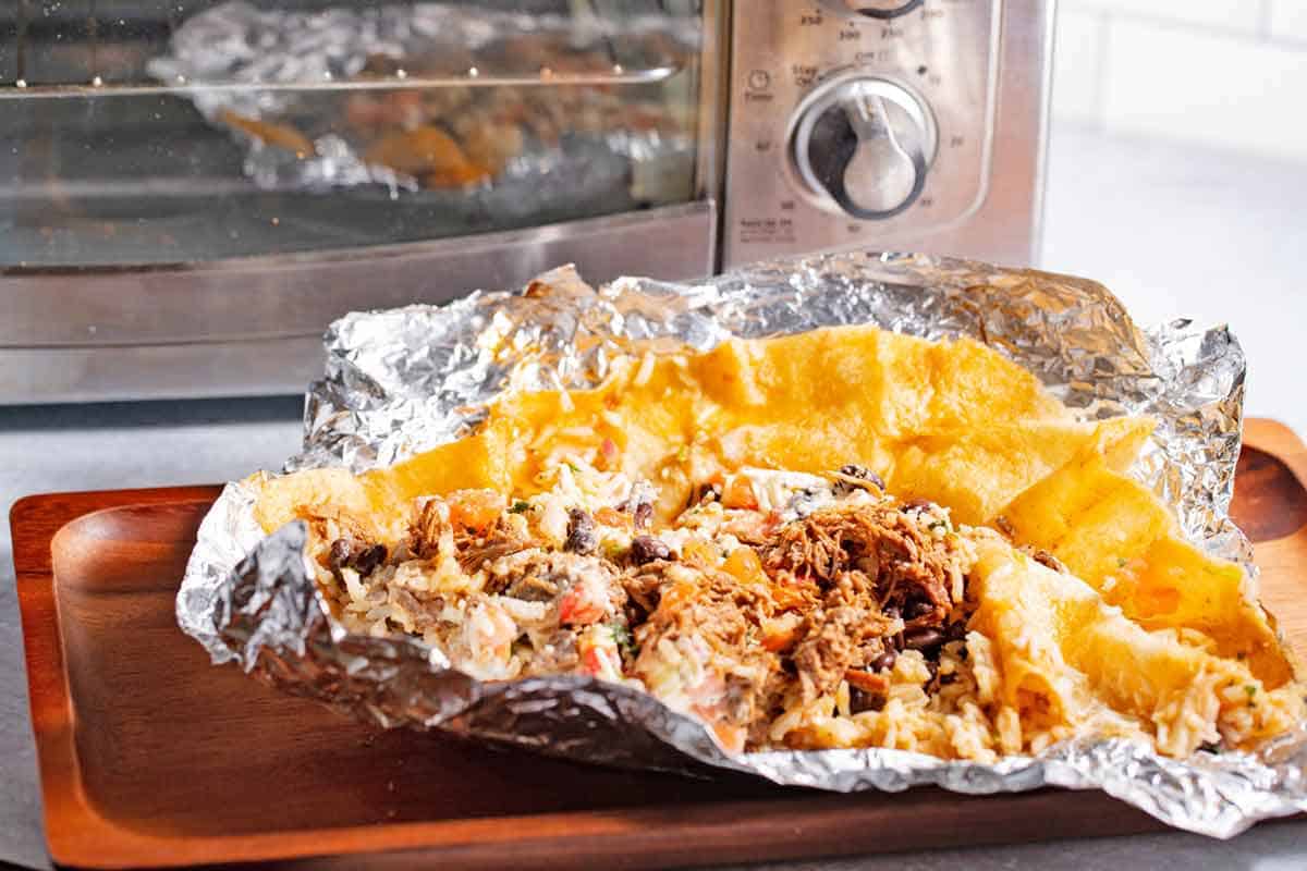 Open burrito in foil ready to be reheated in the toaster oven.
