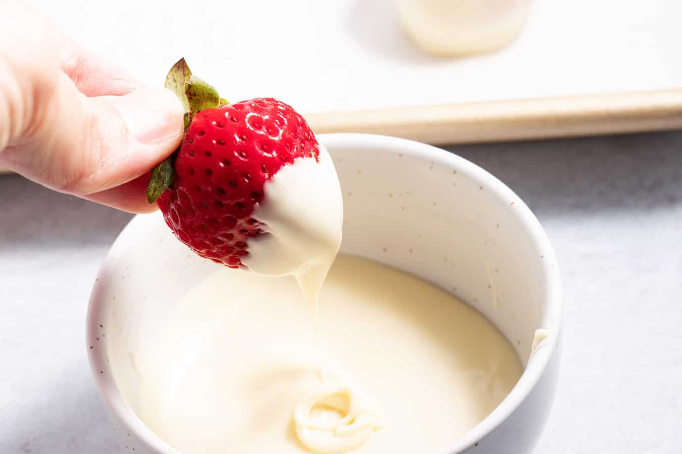 Strawberry being dipped in white chocolate.
