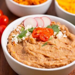 Bowl of canned refried beans that are like restaurant style with with garnishes.