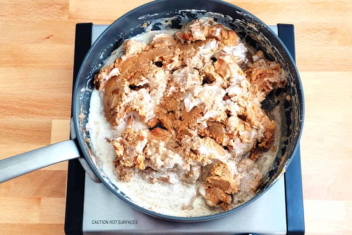 Canned refried beans cooking with cream in pan.
