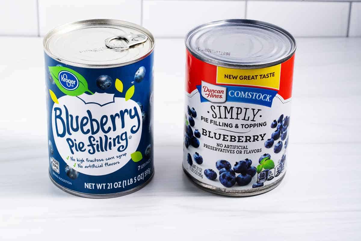 Two cans of blueberry pie filling.