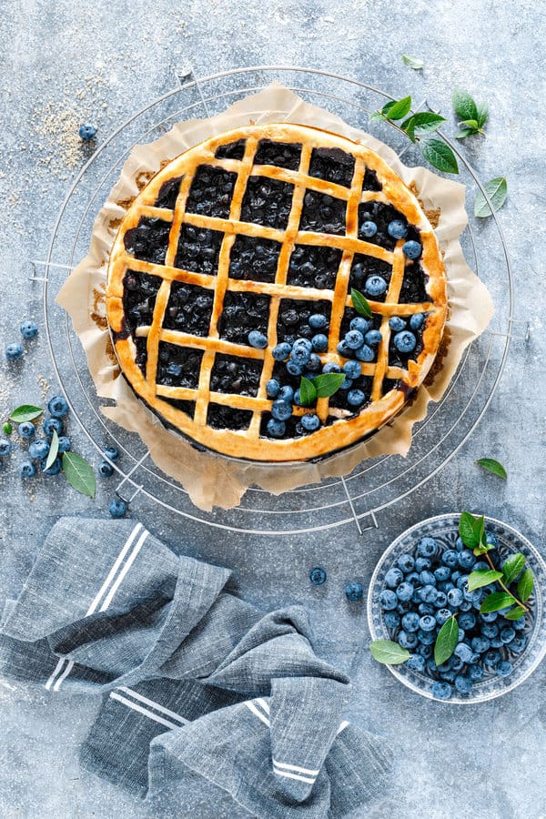 Blueberry pie with plate of blueberries.