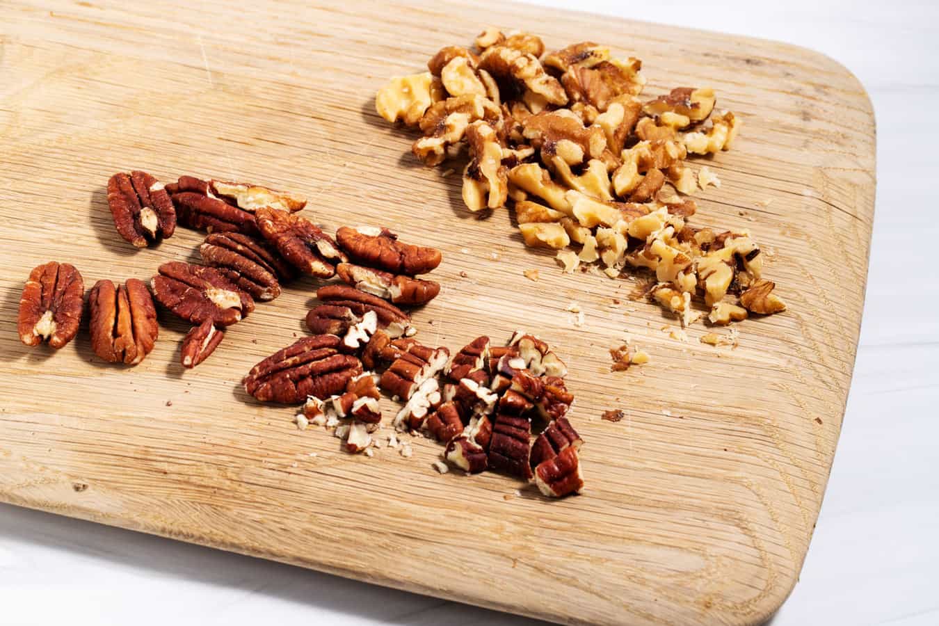 Chopped pecans and walnuts on cutting board.