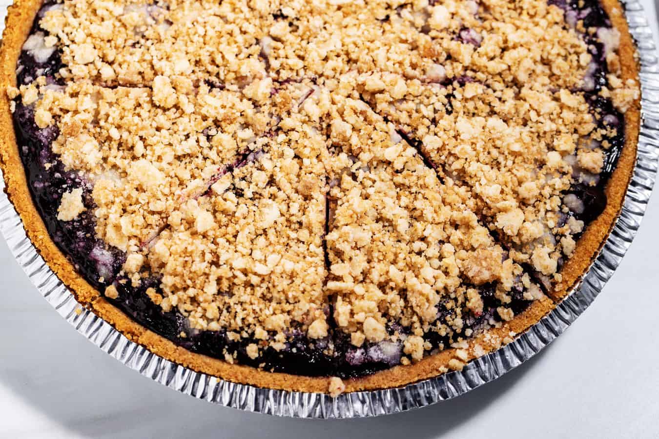 Blueberry pie with premade graham cracker crust and streusel topping cut in quarter slices.