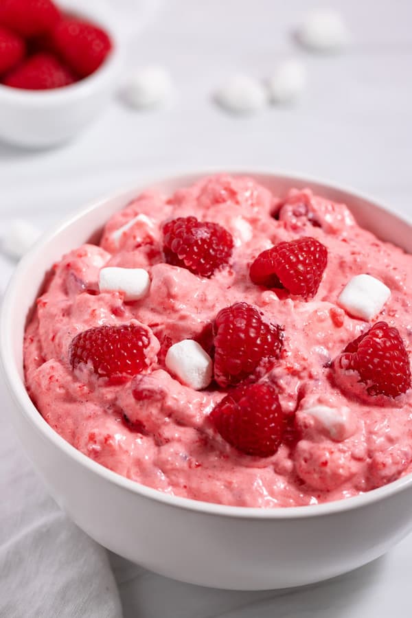 cranberry raspberry jello salad recipe in a bowl garnished with raspberries