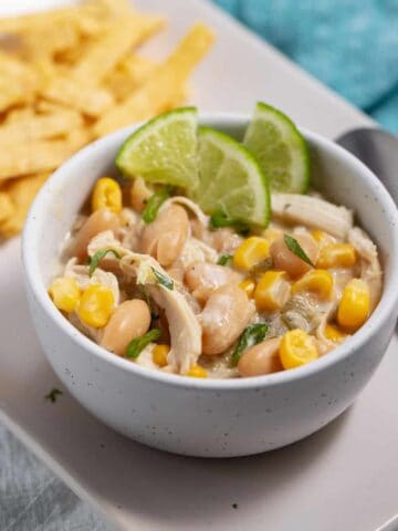 bowl of white chicken chili with salsa verde garnished with lime wedges