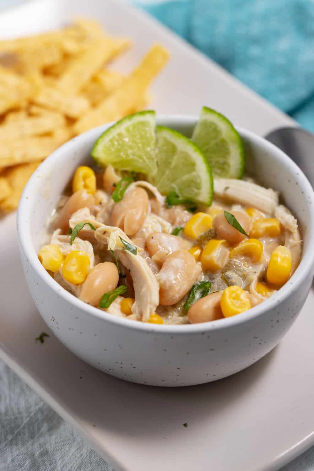 bowl of white chicken chili with salsa verde garnished with lime wedges