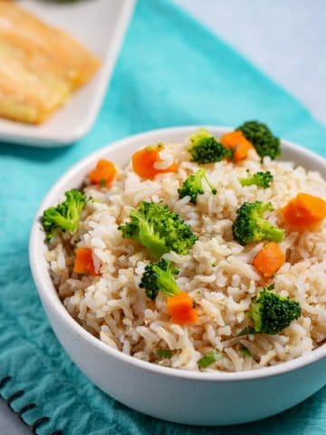bowl of brown rice with veggies and plate of fish