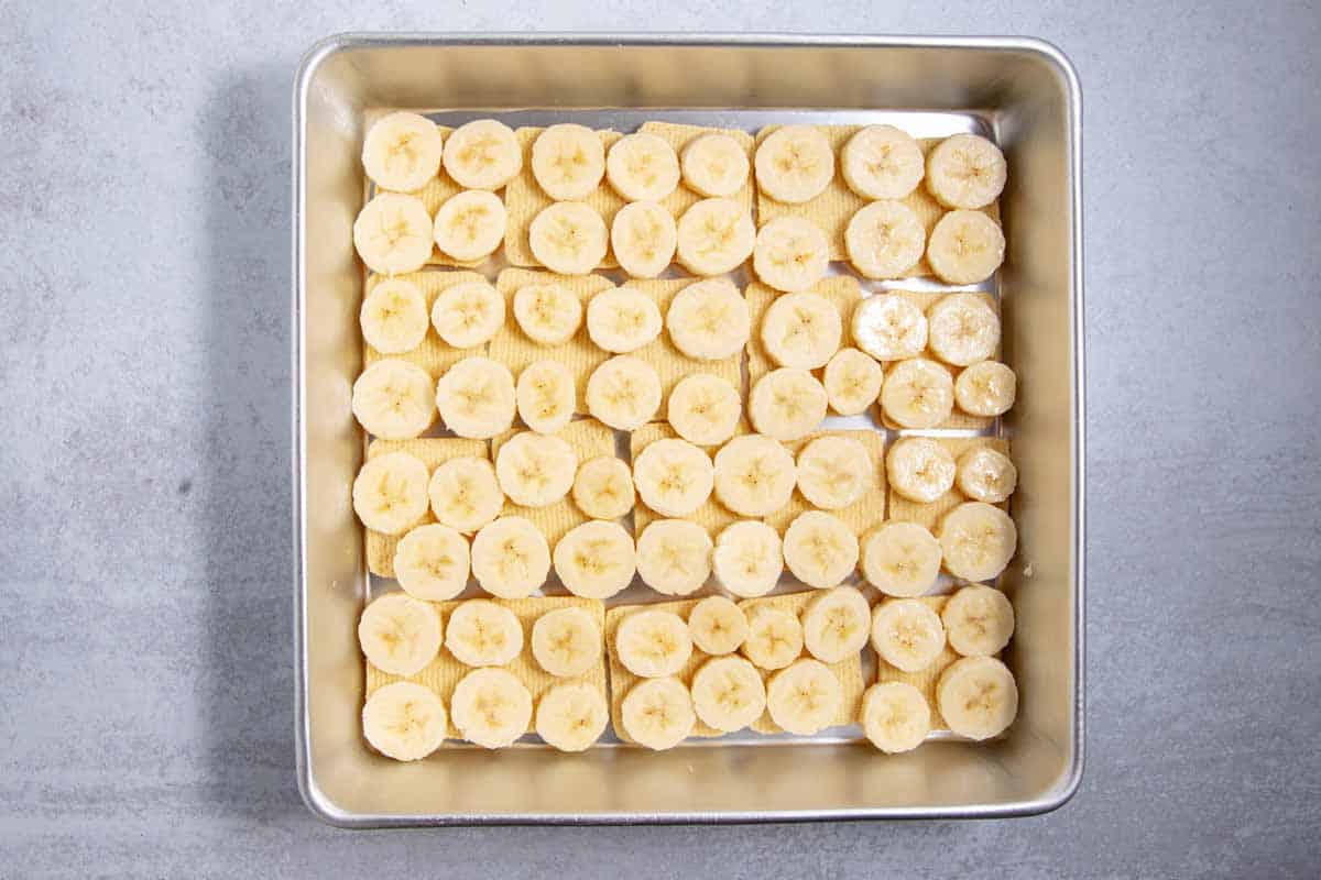 banana layered on top of Chessmen cookies in the pan