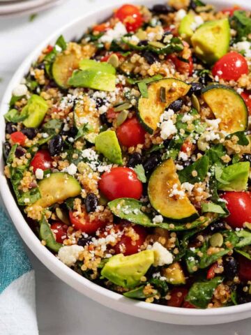 bowl of quinoa black bean salad with zucchini, spinach, and avocado