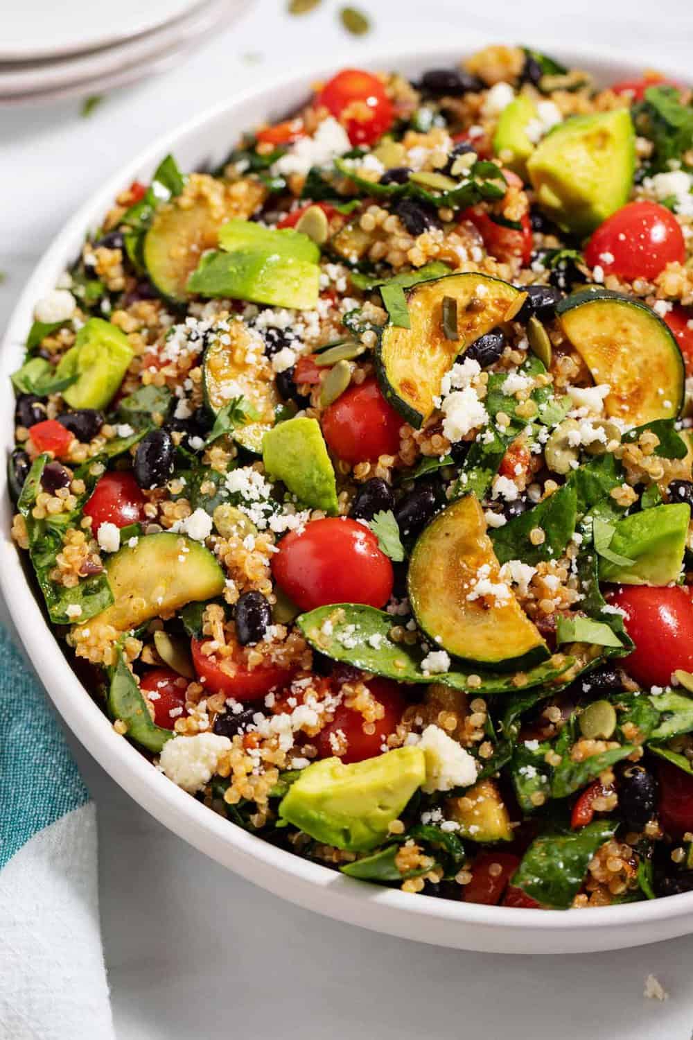 bowl of quinoa black bean salad with zucchini, spinach, and avocado