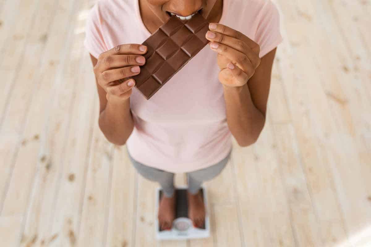 woman eating chocolate on scale
