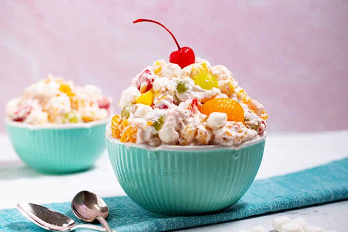 Bowl of ambrosia salad with a cherry on top.