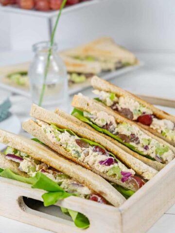 serving container of chicken salad sandwiches with grapes