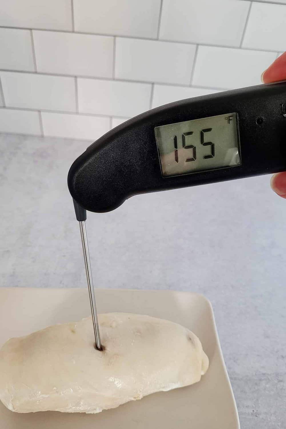 food thermometer in cooked chicken showing temperature of 155 degrees F