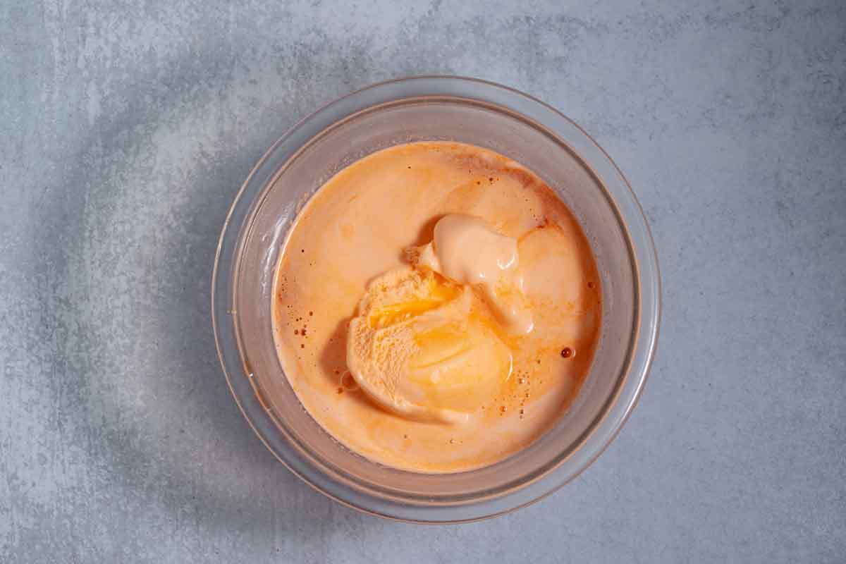 orange sherbet melting in a bowl of dissolved jello