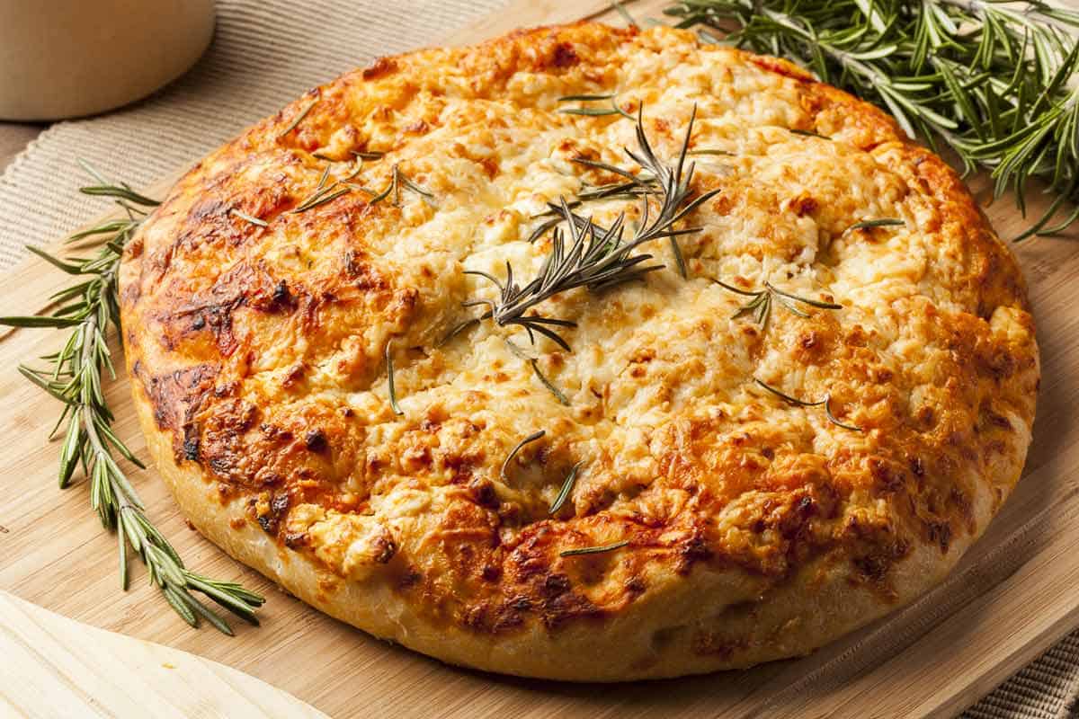 Round focaccia bread with a rosemary garnish.