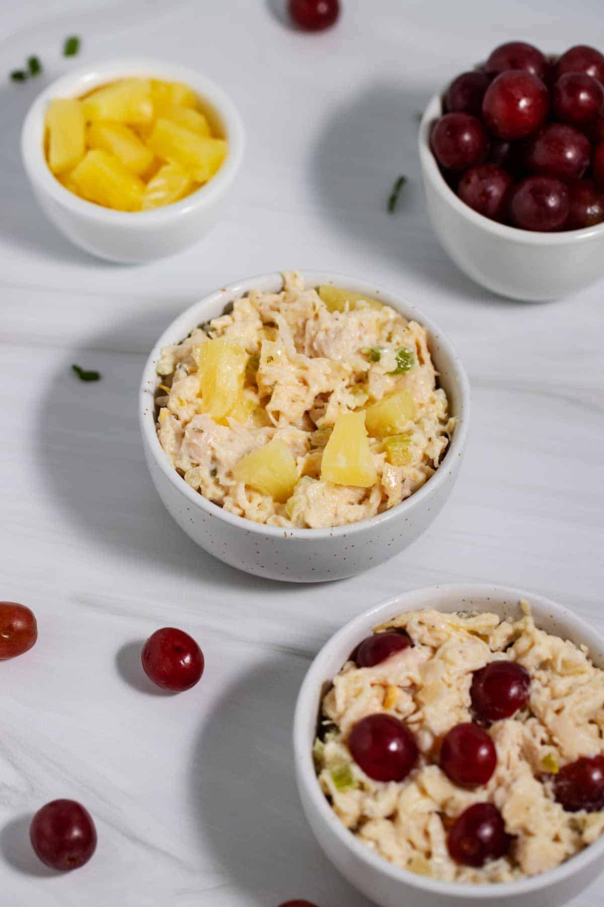 Bowls of store-bought chicken salad with pineapple and grapes to make it taste better.