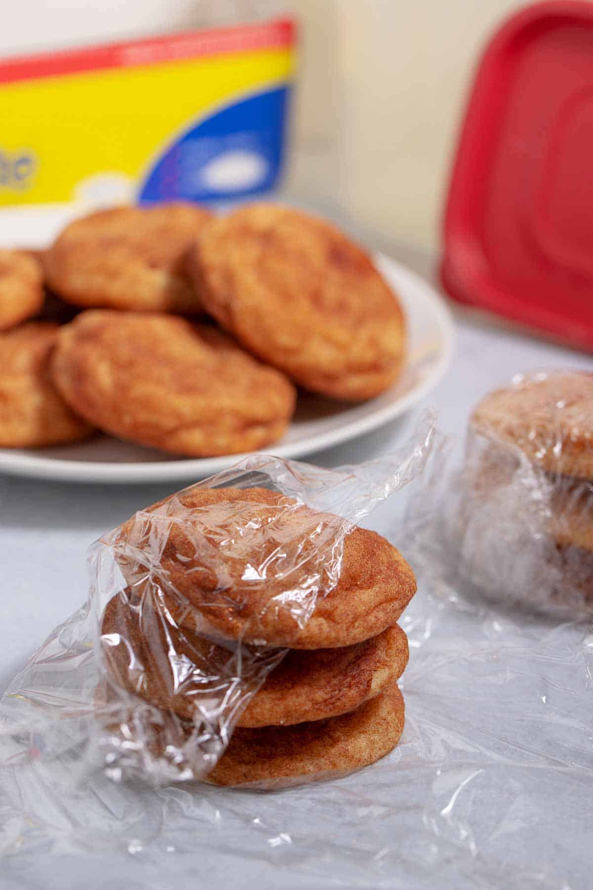 Wrapping snickerdoodle cookies in plastic wrap to freeze.