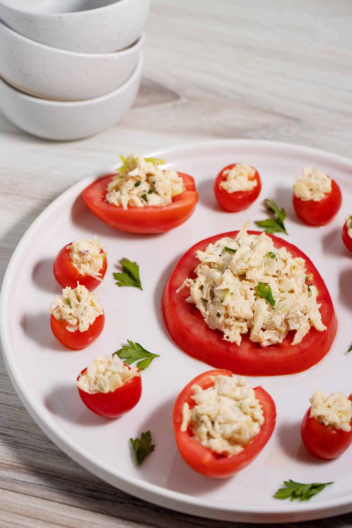 Chicken salad spread on a tomato slice and stuffed in cherry tomatoes and half of a Roma tomato.