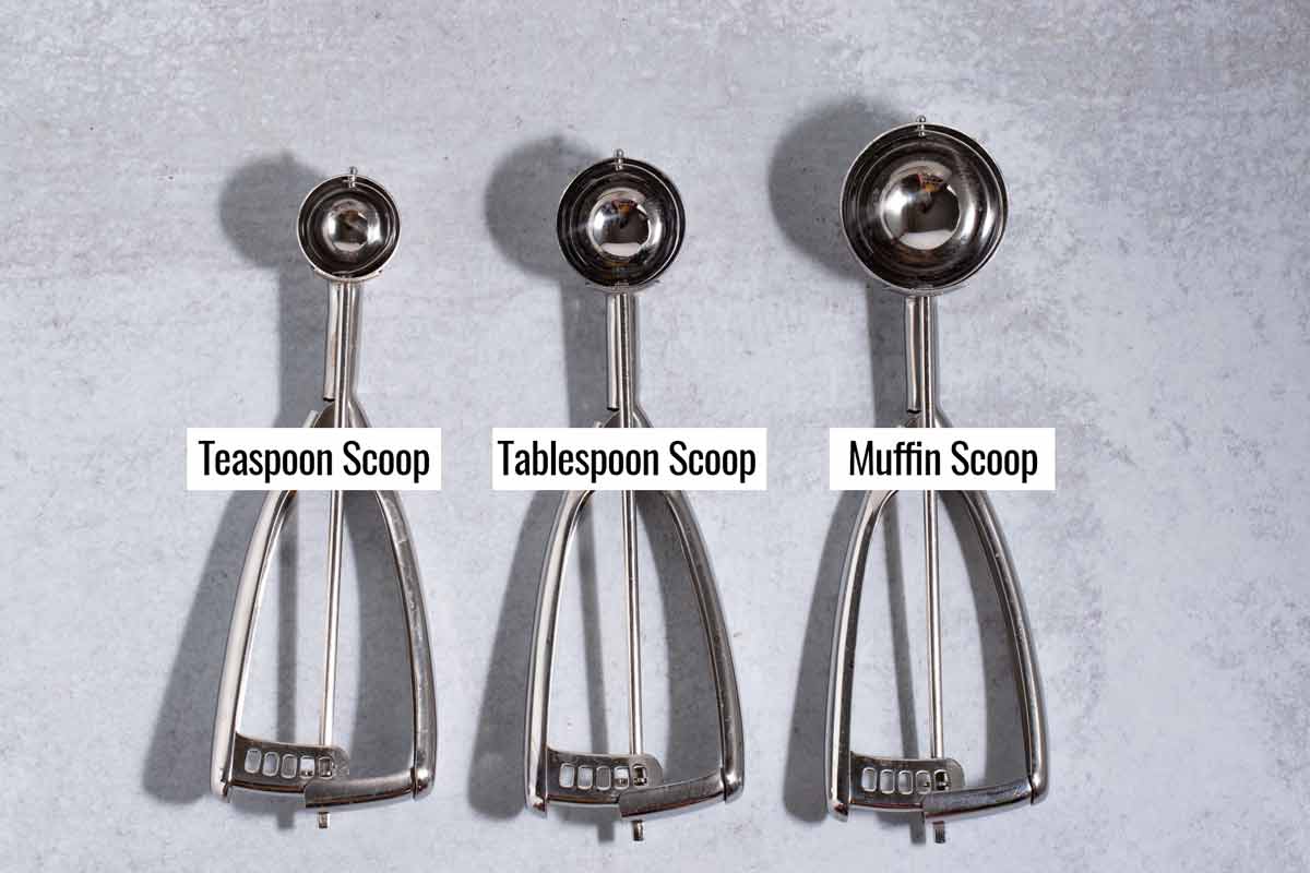 Three sizes of cookie scoops lined up (teaspoon, tablespoon, and muffin scoop).