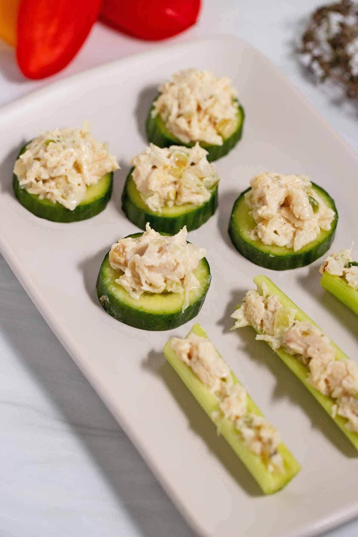 Plate of chicken salad veggie appetizers. Chicken salad is spread on cucumber slices and in the hollows of celery.