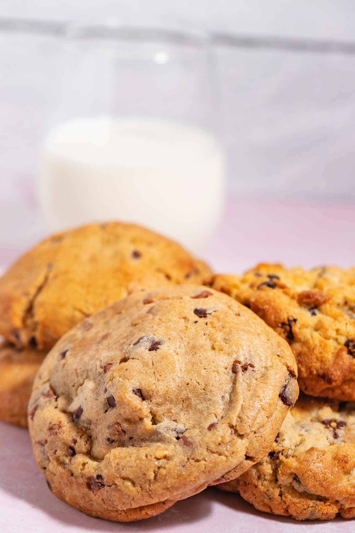 Casual pile of bakery-style cookies with a glass of milk in the background.