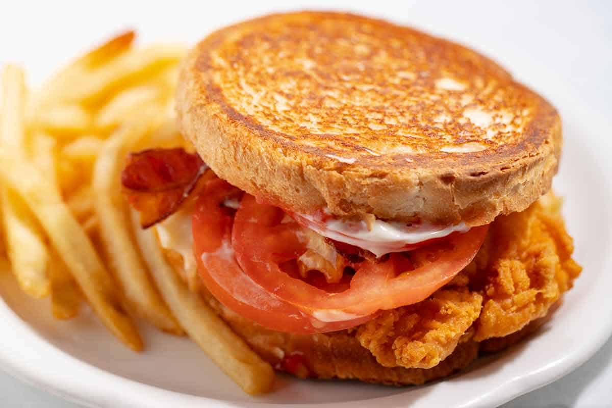 Bacon chicken burger served on sourdough bread with fries on the side.