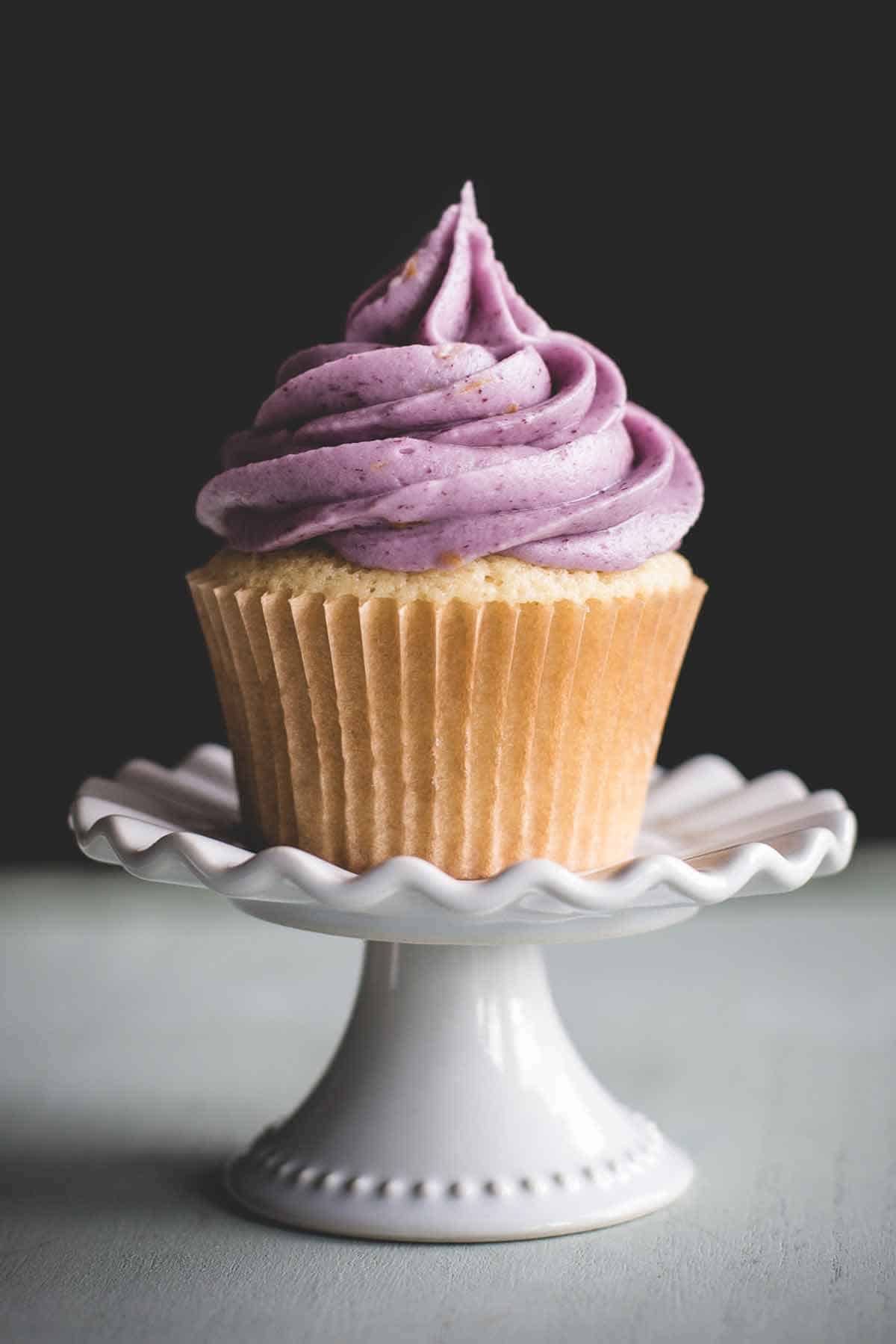Lemon cupcake filled with blueberry filling and topped with blueberry buttercream frosting.