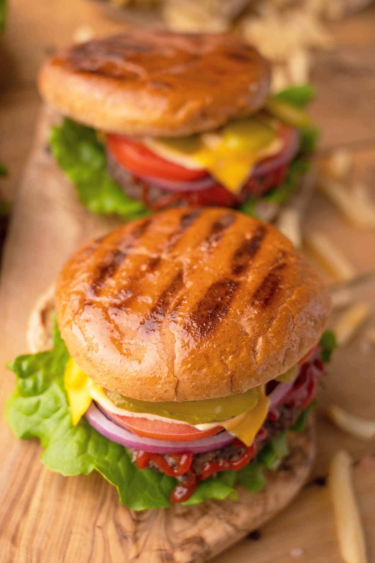 Two burgers on brioche buns with scattered fries.