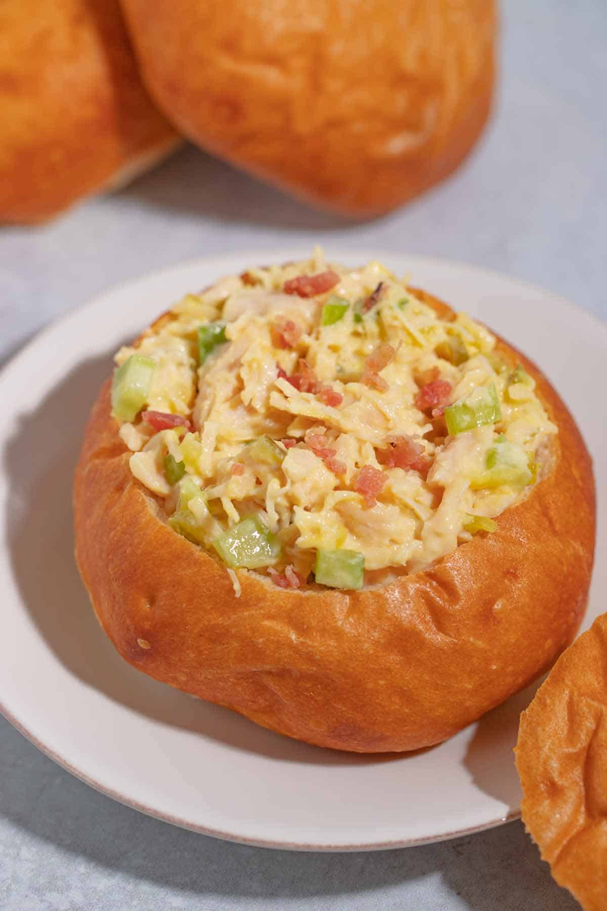 A bread bowl made out of a roll that has been hollowed out with chicken salad inside.