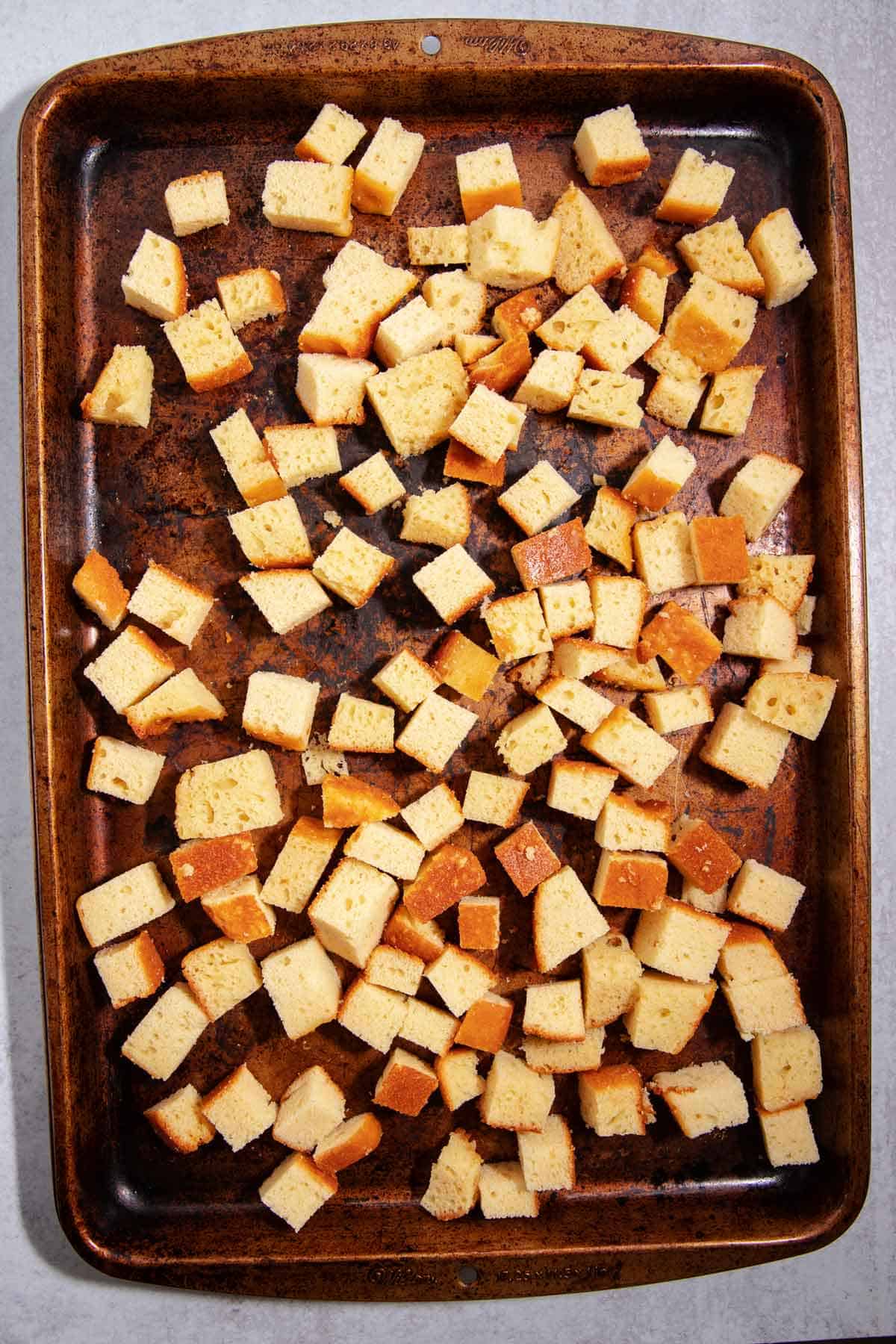 Cake cubes drying out on a baking sheet.